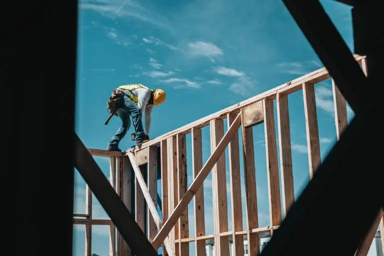 A worker with a yellow hat working on a wooden construction